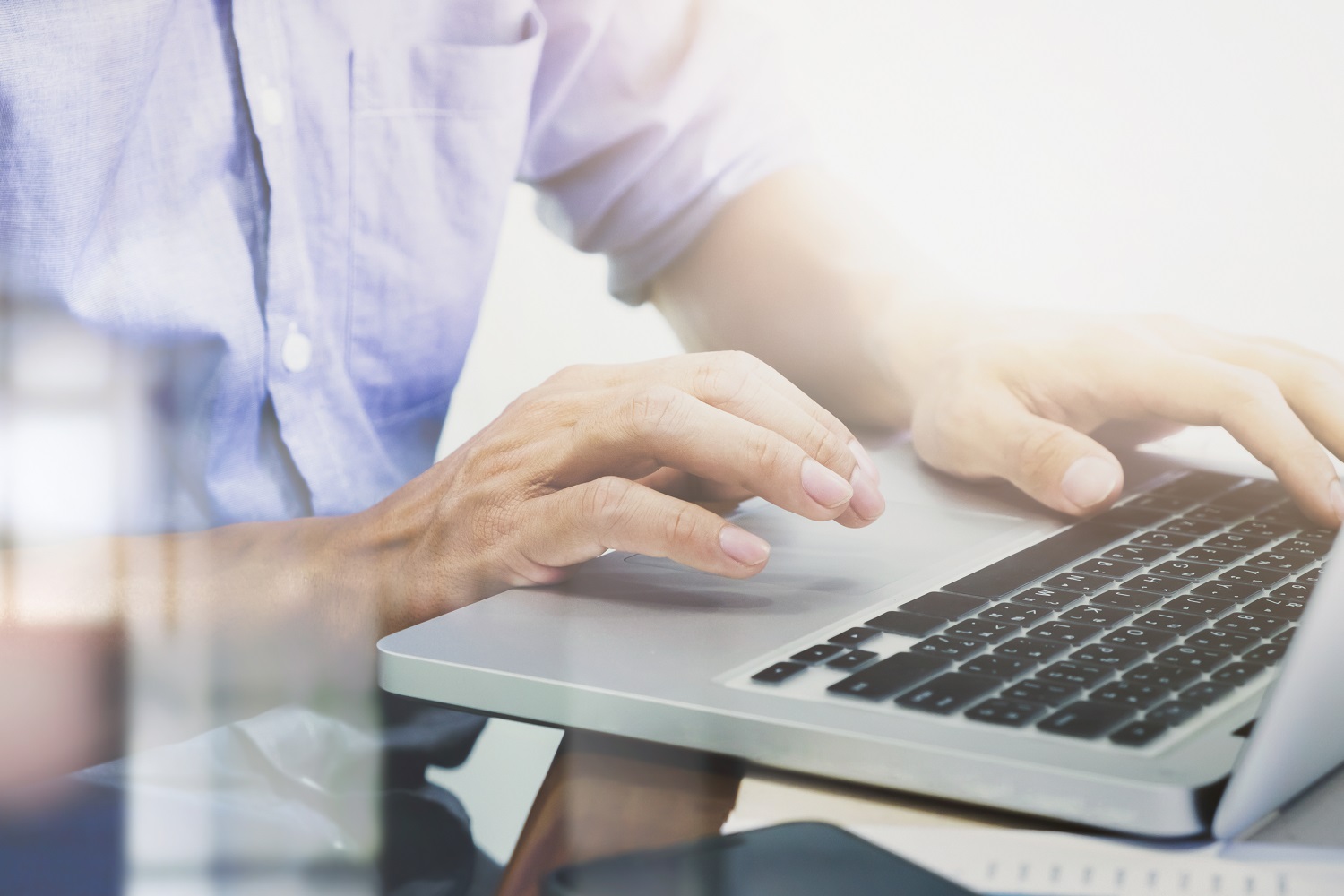 Man's hands typing on laptop keyboard